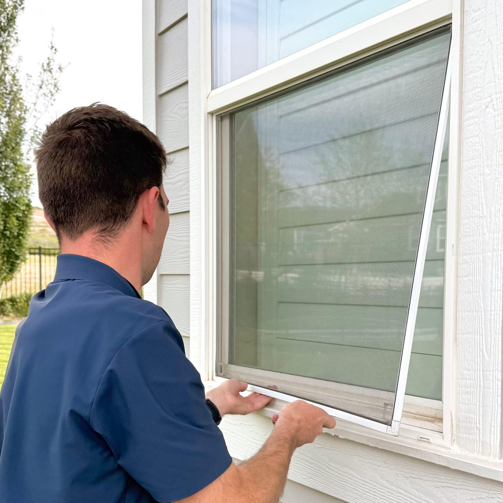 Technician removing a window screen to clean it separately from the glass