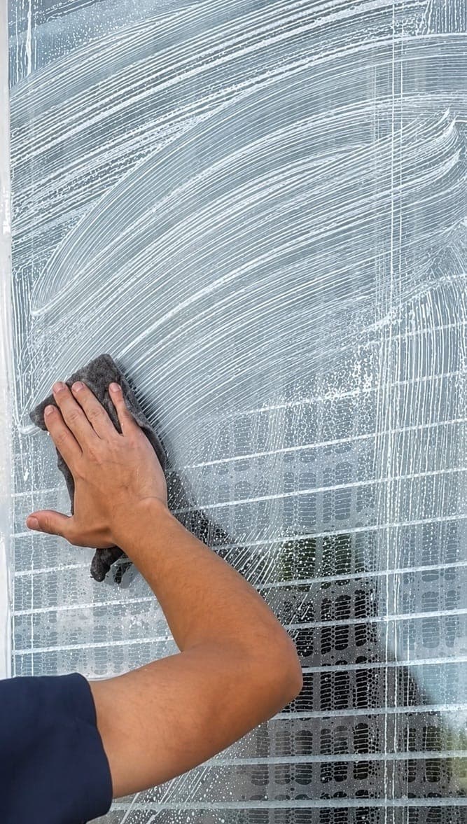 Technician working across a full pane of glass, the kind of surface where mineral film first shows up