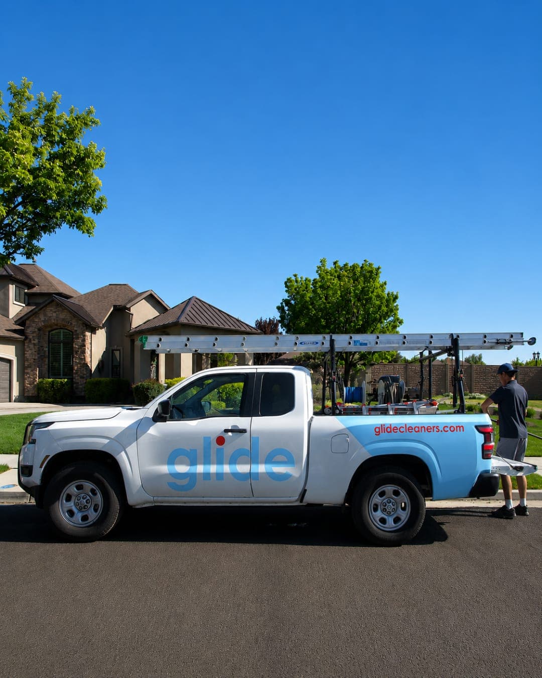 Glide service truck with a ladder rack parked outside a two-story home with upper-level windows
